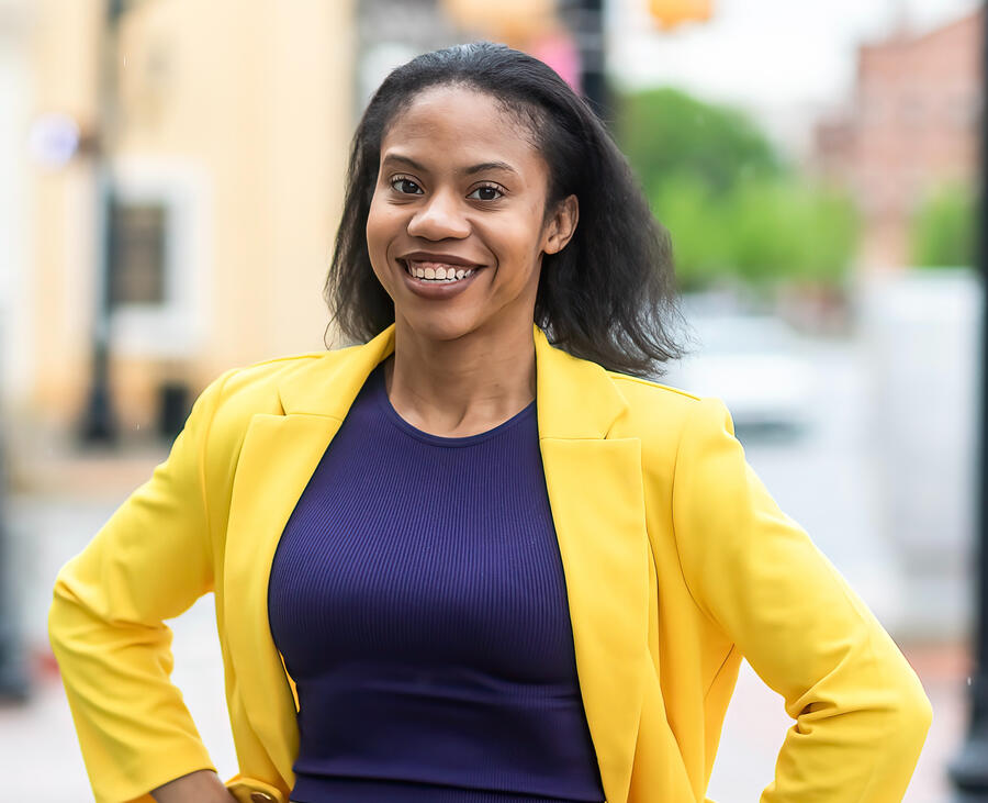 Happy Black Woman wearing a yellow jacket and purple shirt